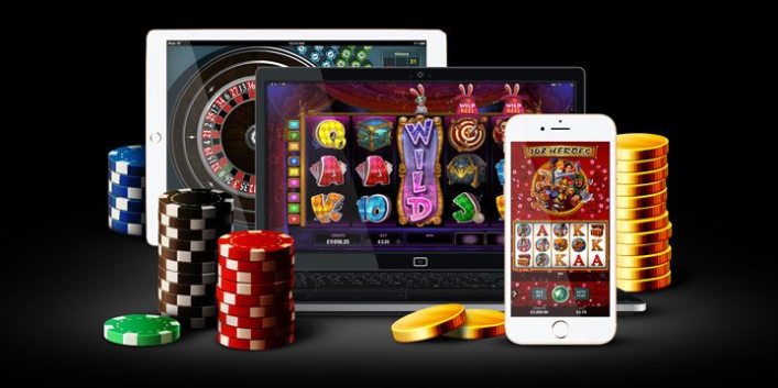 Platta, dator och mobil med casinospel samt spelmarker och guldmynt